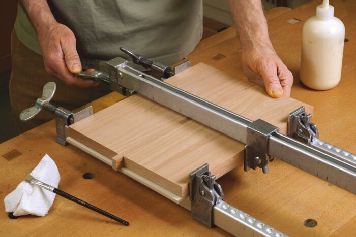 Then cut a piece of melamine a bit smaller than the assembly, and press the pieces against it as you clamp them together tightly. Knock out the spacer block after the glue has dried. 