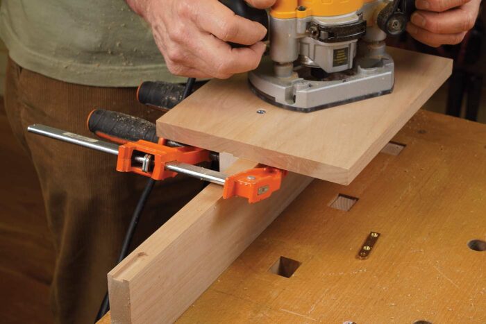 Mortise both ends of the block. Align the opening in the template with your layout mark, clamp the fence to the setup block, and rout a mortise. Then do the same thing at the other end of the setup block.