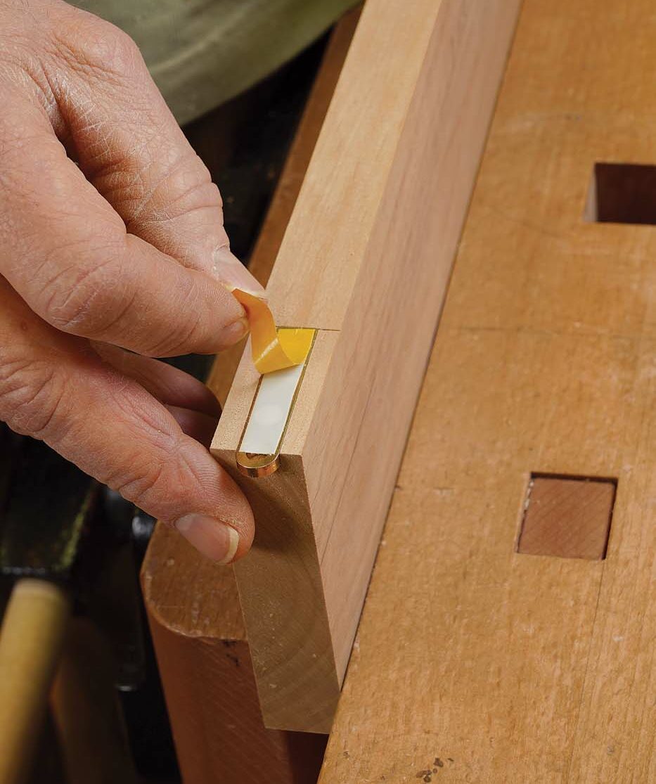 Tape trick. Insert a hinge leaf into the setup block, and apply double-stick tape to it. If the hinge is a bit loose, put just a dot of tape under it as well.