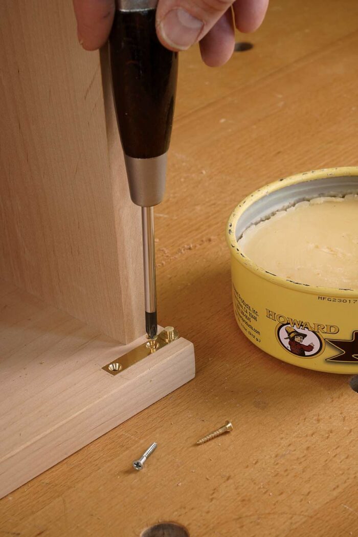 Install the case hinges. Along with brass finish screws, the hinges come with steel screws for cutting threads in the wood so you don’t mar the heads of the brass screws when you install them. Wax the screws to further ease the way.