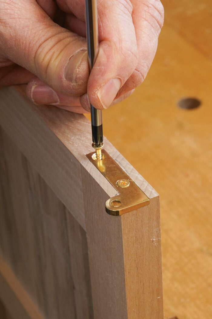 Hang the door. Screw all of the hinge leaves in place, except the leaf in the top edge of the door.