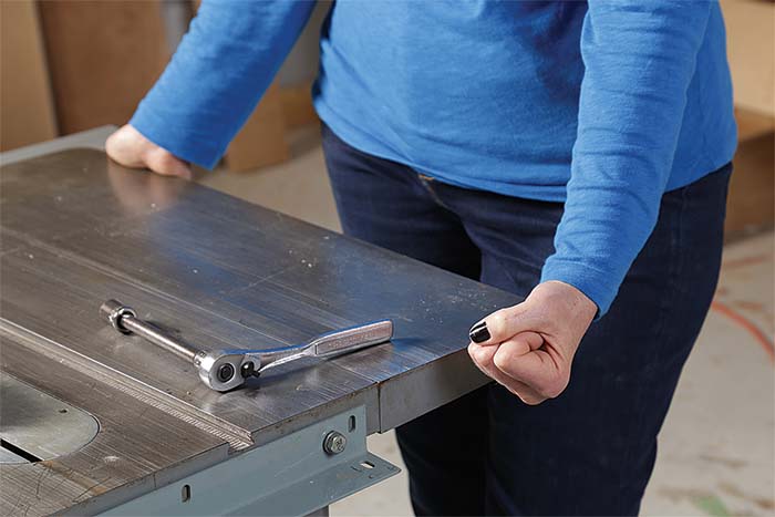 After loosening three of the bolts that attach the top to the cabinet, use the tight bolt as a pivot point to bring the miter slot into parallel with the blade.